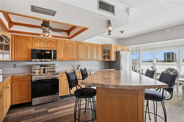 kitchen with stainless steel appliances, a kitchen breakfast bar, visible vents, and a tray ceiling