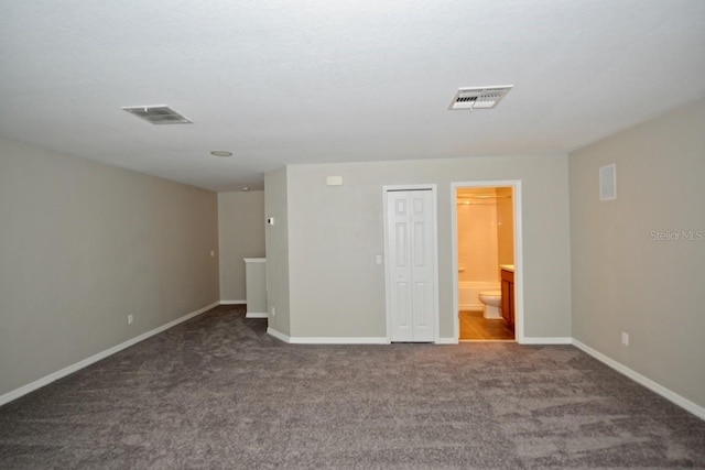 unfurnished bedroom featuring visible vents, dark carpet, and baseboards