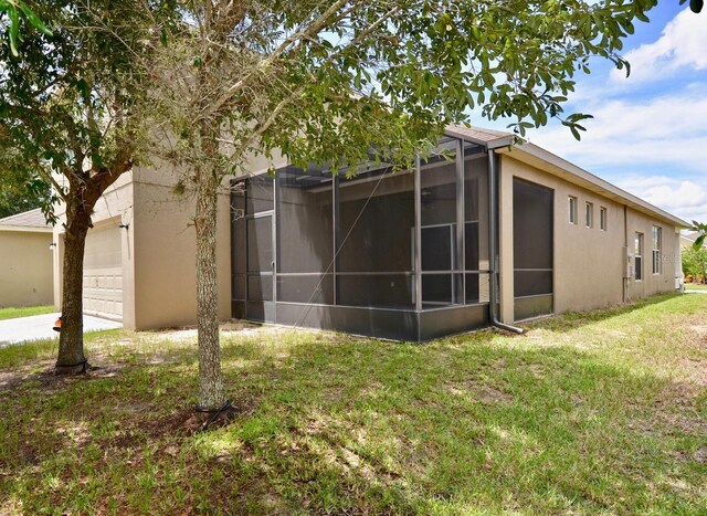 view of home's exterior featuring a lanai, a yard, an attached garage, and stucco siding