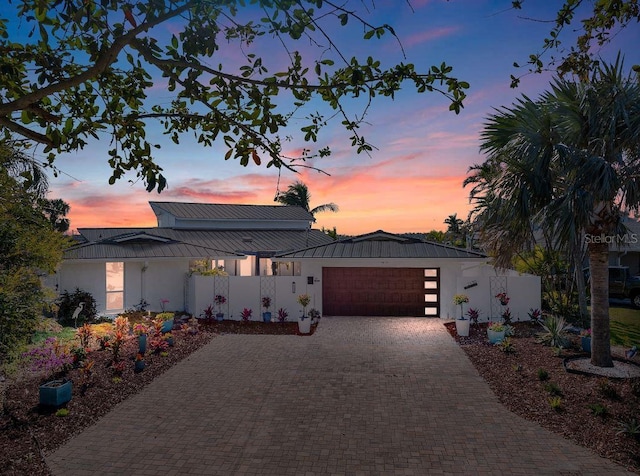 view of front facade featuring metal roof, a garage, fence, decorative driveway, and stucco siding