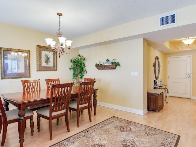 dining area with an inviting chandelier, light wood-style flooring, visible vents, and baseboards