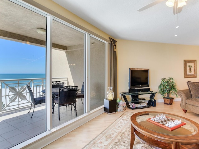 living area featuring a water view, ceiling fan, a textured ceiling, and wood finished floors