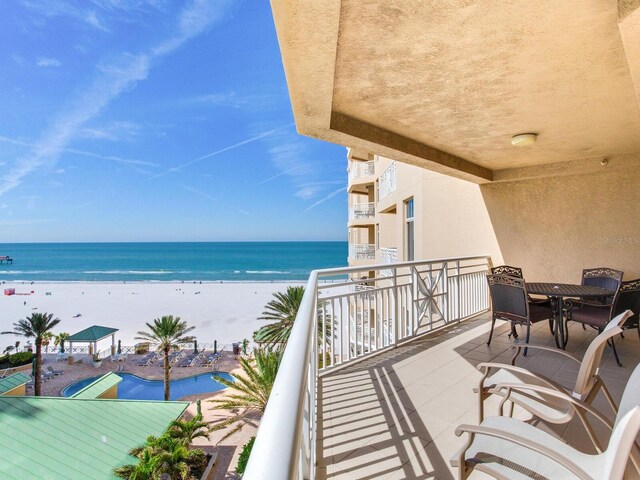 balcony with a view of the beach, a water view, and outdoor dining space