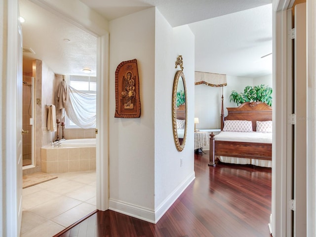 corridor with a textured ceiling, baseboards, and wood finished floors