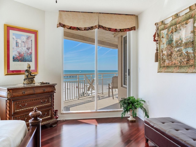 bedroom featuring access to outside, dark wood-style flooring, a water view, and baseboards