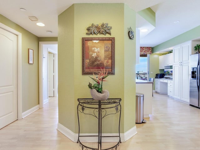 hall featuring light wood-type flooring and baseboards