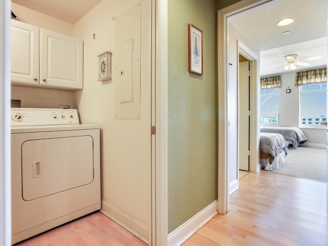 clothes washing area with washer / dryer, electric panel, baseboards, and cabinet space