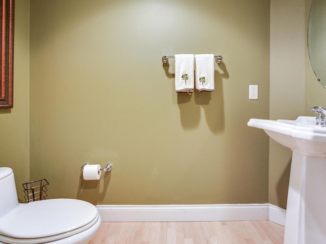 bathroom with baseboards, a sink, toilet, and wood finished floors