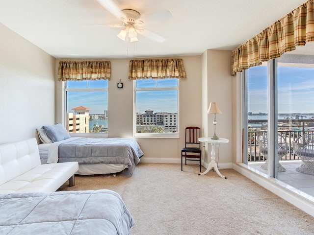 carpeted bedroom with a view of city, access to outside, ceiling fan, and baseboards