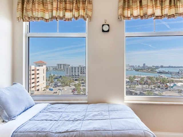 bedroom featuring a city view, a water view, and multiple windows