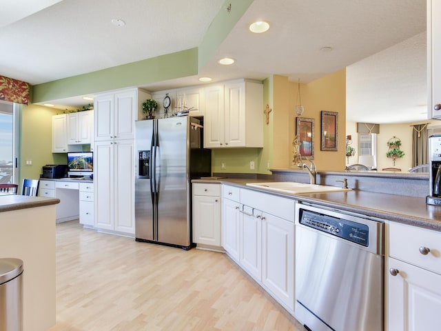 kitchen featuring recessed lighting, a sink, white cabinets, appliances with stainless steel finishes, and light wood finished floors