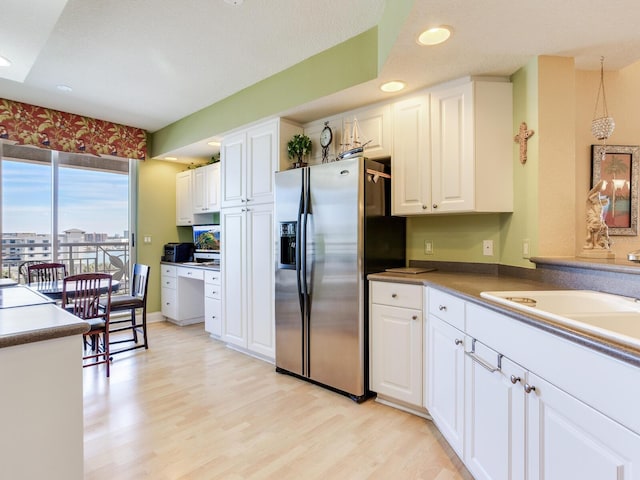 kitchen featuring pendant lighting, recessed lighting, light wood-style floors, white cabinetry, and stainless steel fridge with ice dispenser