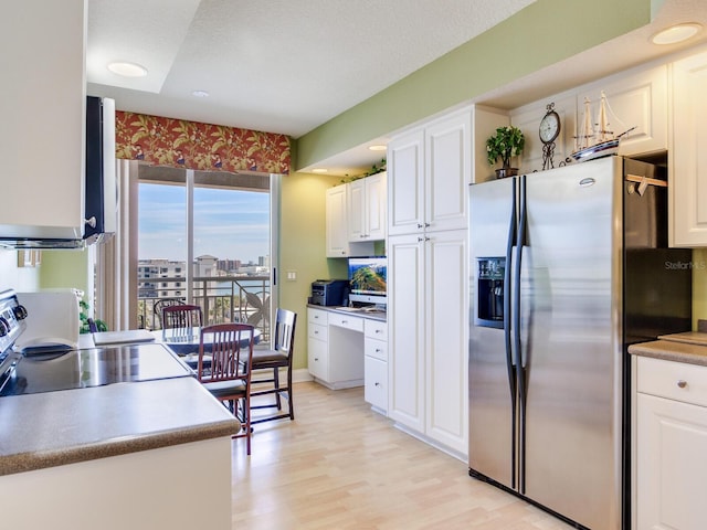 kitchen featuring light wood finished floors, electric range, stainless steel fridge, and white cabinetry