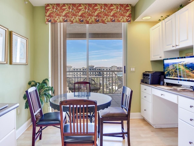 dining room with baseboards, built in desk, and light wood-style floors