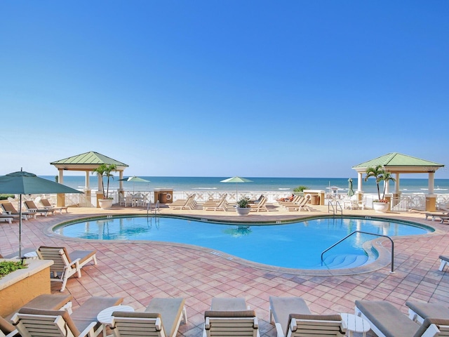 community pool featuring a gazebo, a patio, and a water view