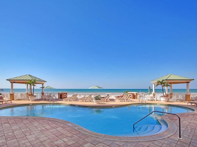 pool featuring a water view, a patio, and a gazebo