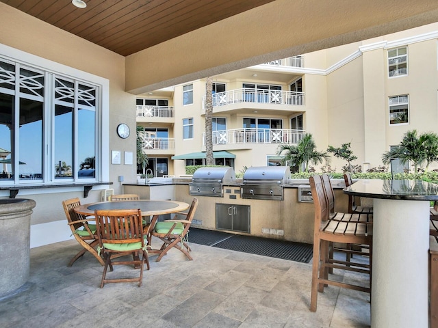 view of patio / terrace featuring a sink, outdoor dining area, area for grilling, and a grill