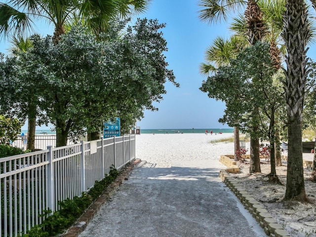 exterior space with a water view, fence, and a beach view