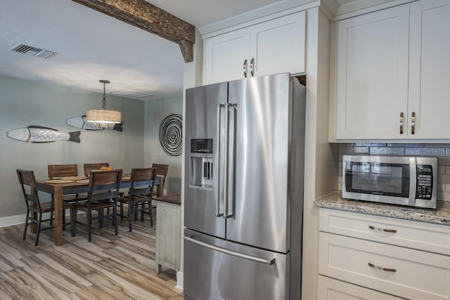 kitchen with decorative backsplash, stainless steel appliances, white cabinets, and light wood-type flooring