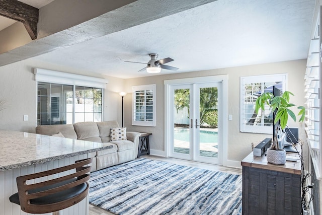 living room with ceiling fan, wood-type flooring, french doors, and a textured ceiling