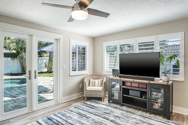 living area with ceiling fan, wood-type flooring, french doors, and a textured ceiling