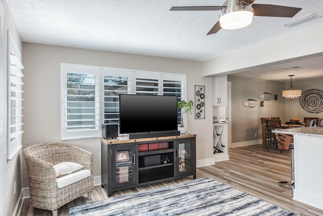 living room with ceiling fan, hardwood / wood-style flooring, and a textured ceiling