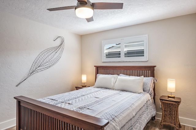 bedroom with ceiling fan, hardwood / wood-style floors, and a textured ceiling