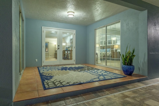 doorway featuring tile patterned flooring, french doors, and a textured ceiling