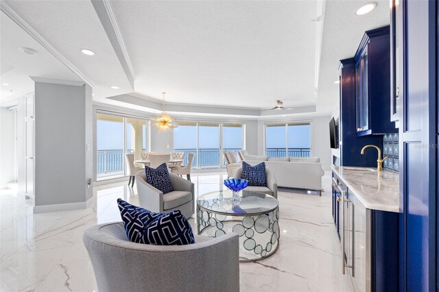 living room featuring a tray ceiling, marble finish floor, and a textured ceiling