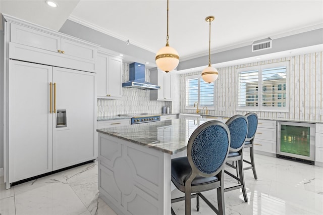 kitchen featuring wine cooler, marble finish floor, crown molding, wall chimney range hood, and paneled refrigerator