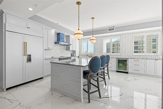 kitchen with wall chimney exhaust hood, wine cooler, marble finish floor, crown molding, and paneled fridge