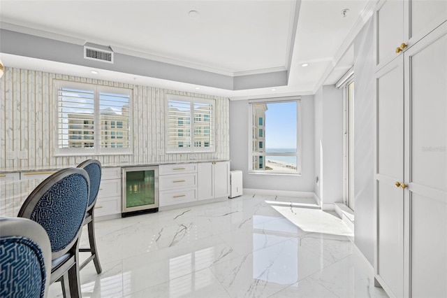 interior space featuring wine cooler, visible vents, marble finish floor, a raised ceiling, and crown molding