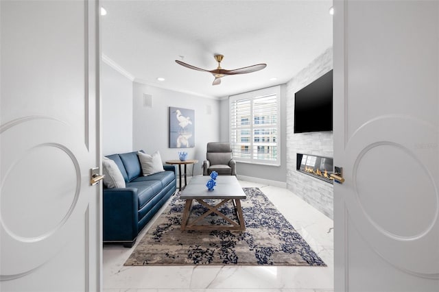 living room featuring a ceiling fan, a glass covered fireplace, ornamental molding, marble finish floor, and a textured ceiling