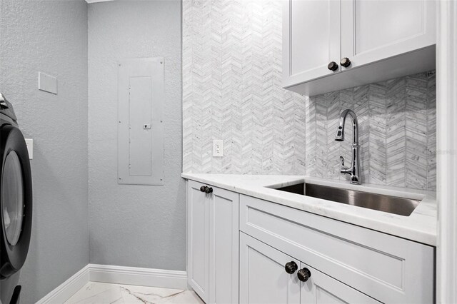 clothes washing area featuring a sink, baseboards, marble finish floor, cabinet space, and electric panel