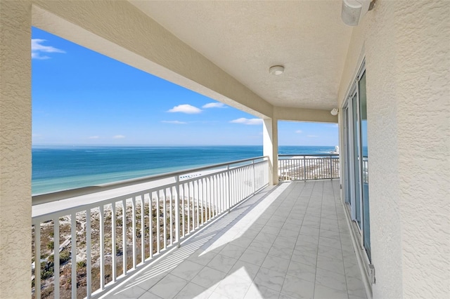 balcony featuring a water view and a beach view