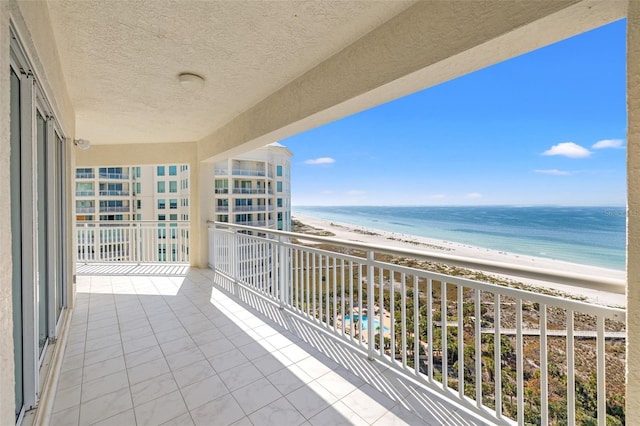 balcony with a water view and a view of the beach