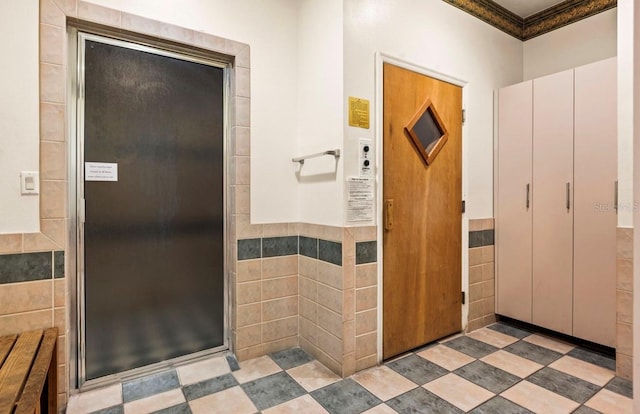 full bath featuring a wainscoted wall, tile walls, and walk in shower