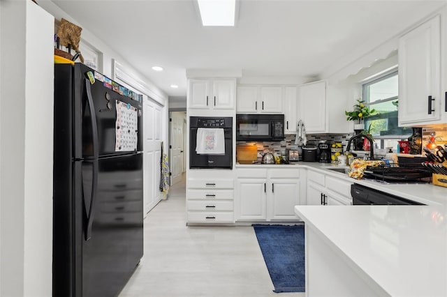 2419 Palmwood Dr, Holiday, FL 34690 - kitchen featuring tasteful backsplash, sink, white cabinets, black appliances, and light wood-type flooring