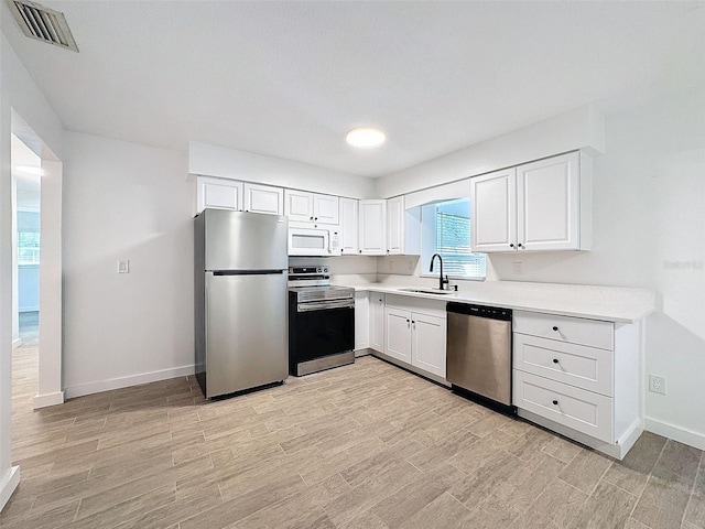 kitchen featuring light wood-type flooring, stainless steel appliances, sink, and white cabinets