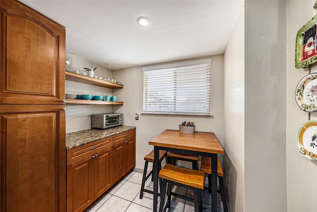6308 Newtown Cir Unit 8C5, Tampa, FL 33615 - kitchen with light tile patterned floors, dark stone counters, open shelves, a toaster, and brown cabinets