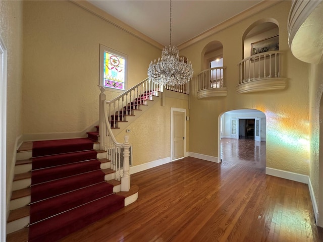 foyer entrance featuring a chandelier, ornamental molding, baseboards, and wood finished floors