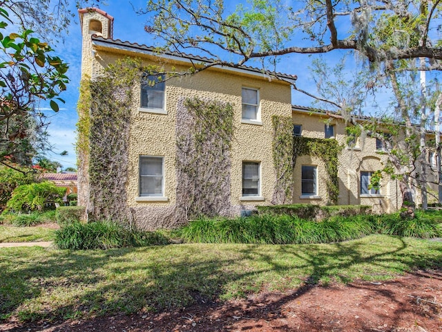 view of home's exterior with stucco siding, a tile roof, and a yard