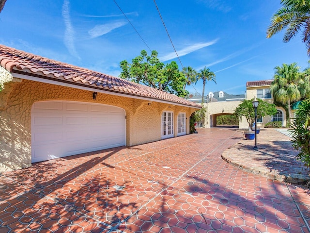 view of home's exterior with stucco siding, a tiled roof, and french doors