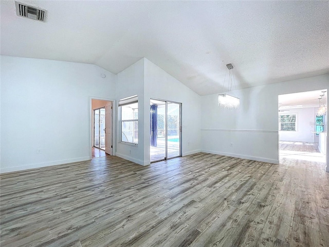 8600 Berkley Dr, Hudson, FL 34667 - spare room featuring hardwood / wood-style flooring, a wealth of natural light, a textured ceiling, and a notable chandelier