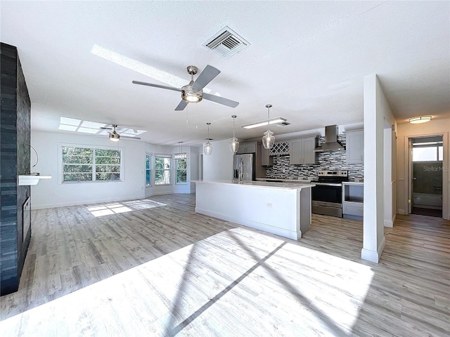 8600 Berkley Dr, Hudson, FL 34667 - kitchen with wall chimney exhaust hood, appliances with stainless steel finishes, gray cabinets, an island with sink, and decorative backsplash