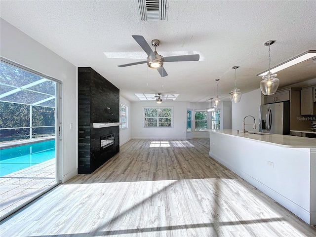 8600 Berkley Dr, Hudson, FL 34667 - kitchen with sink, ceiling fan, light hardwood / wood-style floors, stainless steel refrigerator with ice dispenser, and a textured ceiling