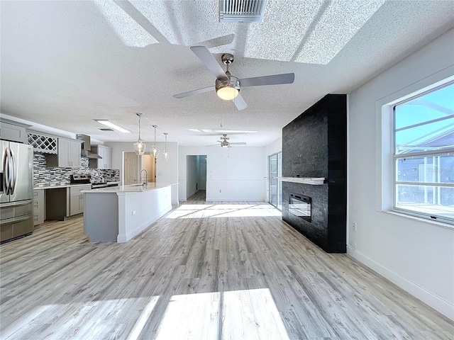 8600 Berkley Dr, Hudson, FL 34667 - kitchen with a textured ceiling, a large fireplace, appliances with stainless steel finishes, light hardwood / wood-style floors, and wall chimney range hood