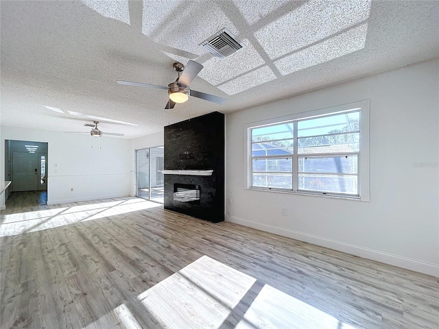 8600 Berkley Dr, Hudson, FL 34667 - unfurnished living room featuring ceiling fan, a large fireplace, a textured ceiling, and light wood-type flooring