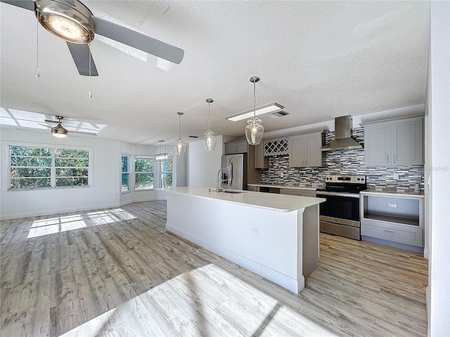 8600 Berkley Dr, Hudson, FL 34667 - kitchen with gray cabinetry, wall chimney range hood, backsplash, and appliances with stainless steel finishes