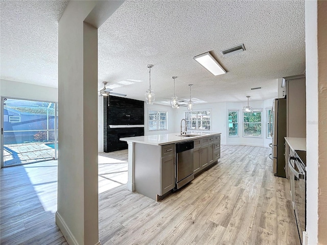 8600 Berkley Dr, Hudson, FL 34667 - kitchen with gray cabinetry, hanging light fixtures, light hardwood / wood-style floors, stainless steel appliances, and a center island with sink